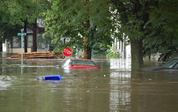 Cars floating down a flooded avenue in a Midwest town